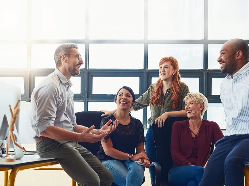 Image of happy team working through ideas in open concept office