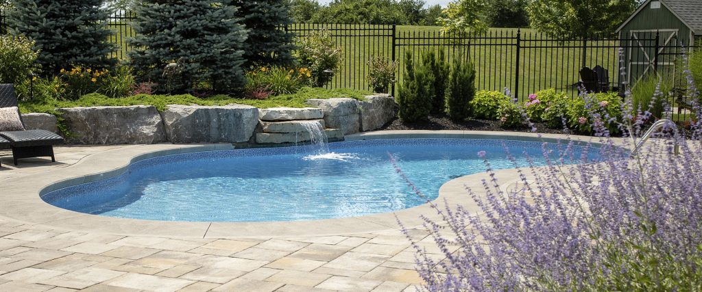 Image of inground pool with rock waterfall in nicely landscaped backyard